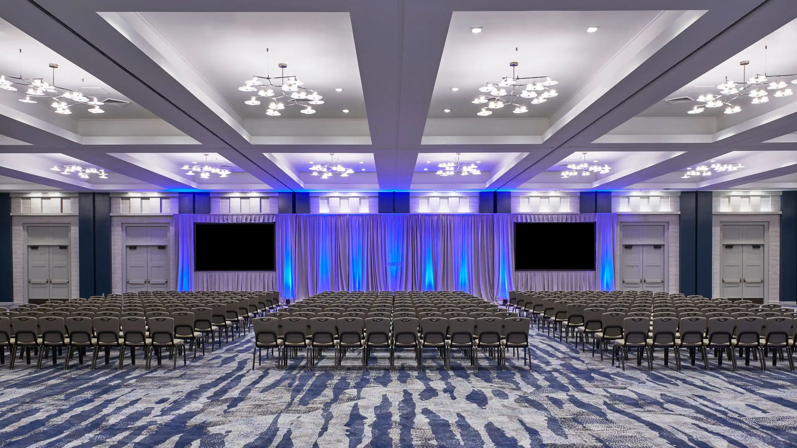 Grand ballroom in theatre seating with stage and blue accent lighting